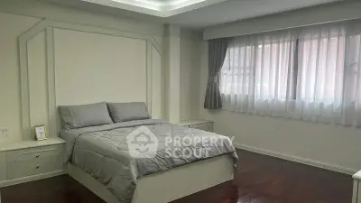 Spacious bedroom with elegant decor and large window for natural light.