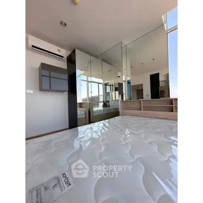 Modern bedroom with mirrored wardrobe and air conditioning in a high-rise apartment.