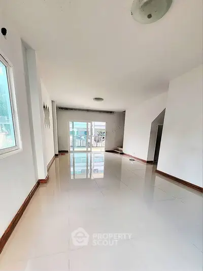 Spacious and bright living room with glossy tiled floors and large windows.