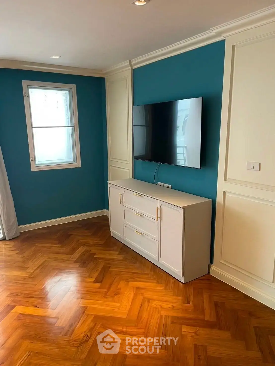 Stylish living room with parquet flooring and mounted TV, featuring elegant blue accent wall.