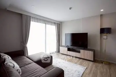 Modern living room with sleek furniture and large TV, featuring elegant curtains and wooden flooring.