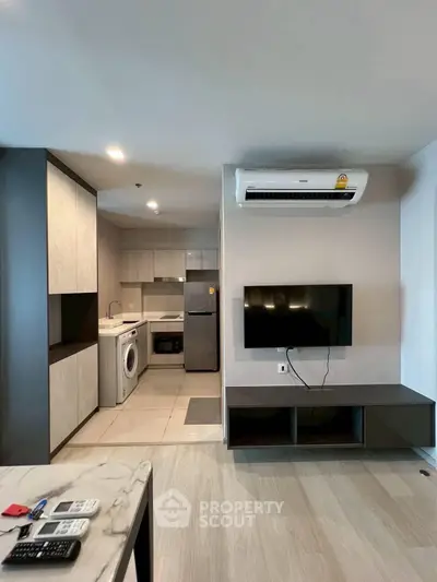 Modern living room with open kitchen, featuring sleek appliances and stylish decor.