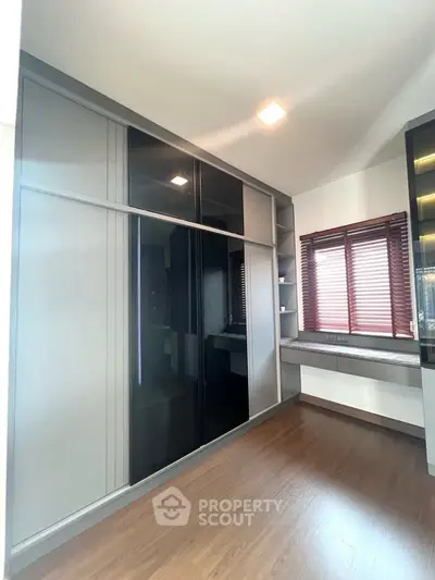 Spacious modern room with sleek built-in wardrobe and wooden flooring