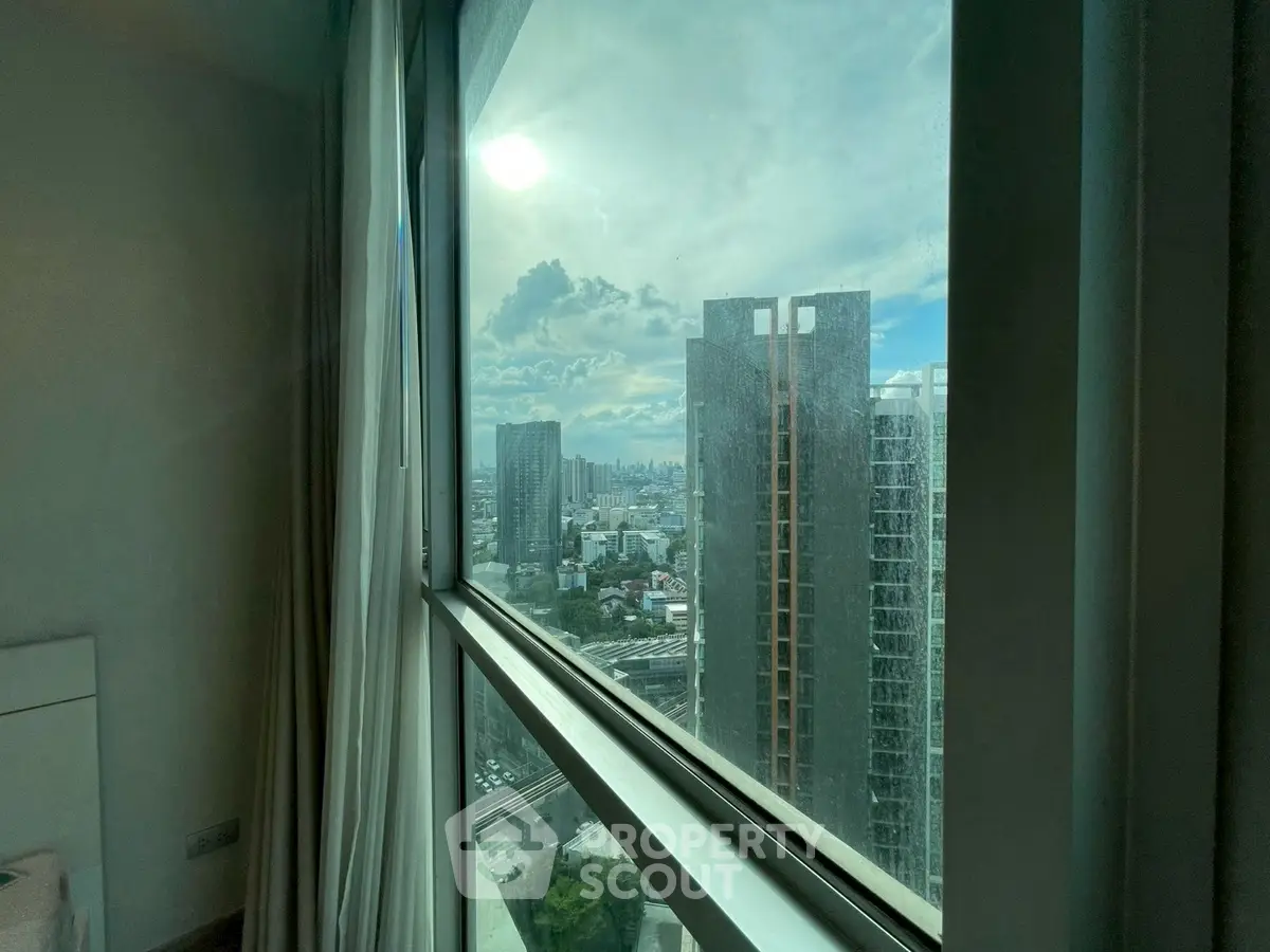 Stunning city view from a high-rise apartment window, showcasing urban skyline and modern architecture.