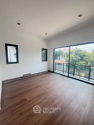 Spacious room with large windows and wooden flooring, offering a bright and airy atmosphere.