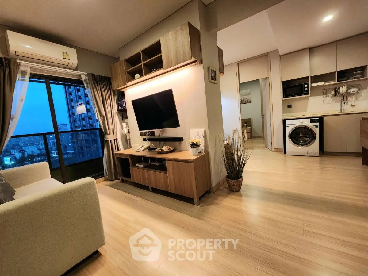 Modern living room with open kitchen and city view balcony in high-rise apartment.