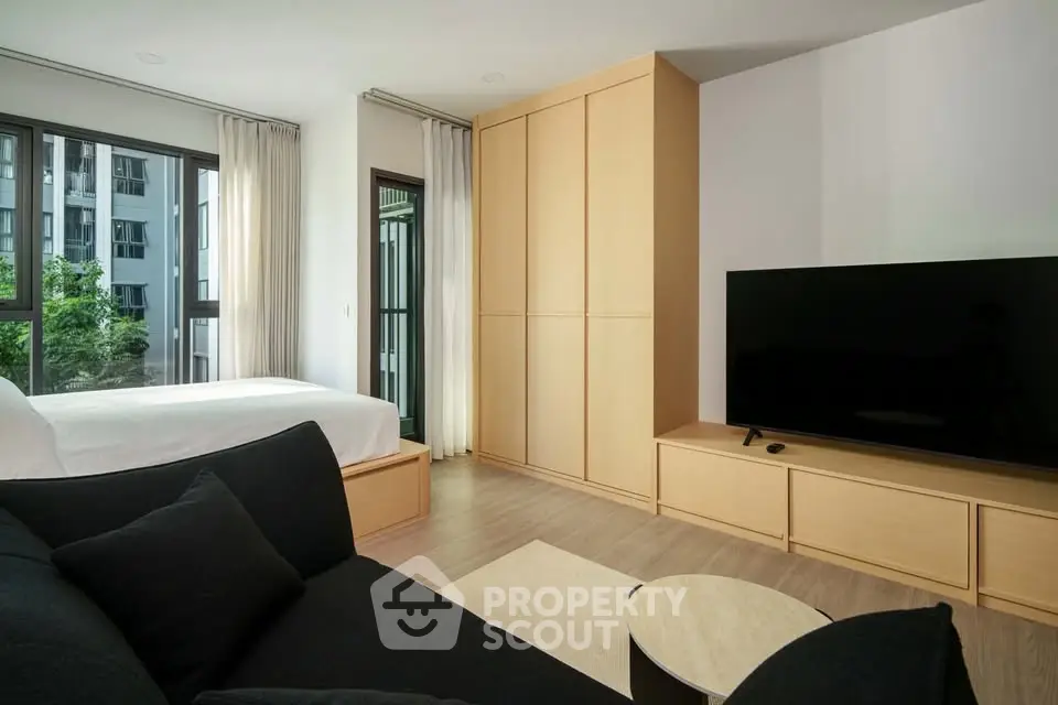 Modern studio apartment with large windows and sleek furnishings