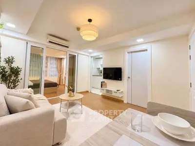 Modern living room with cozy sofa, stylish decor, and open layout leading to bedroom.