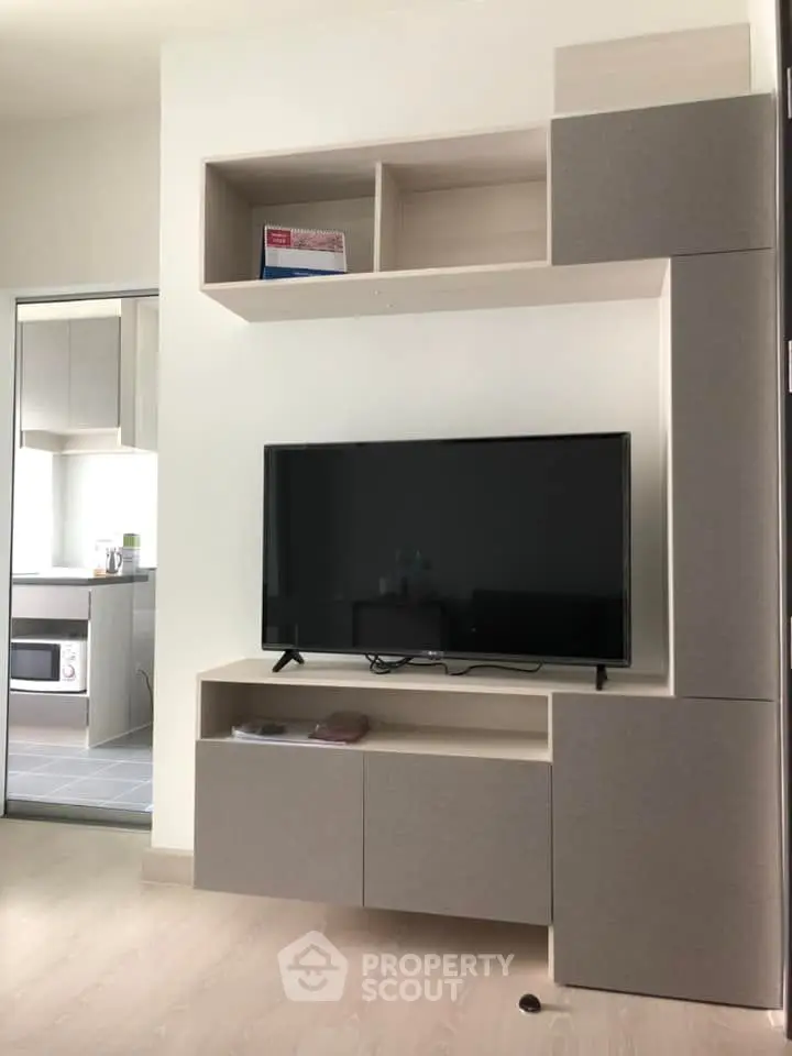 Modern living room with sleek TV unit and open kitchen view, perfect for contemporary living.