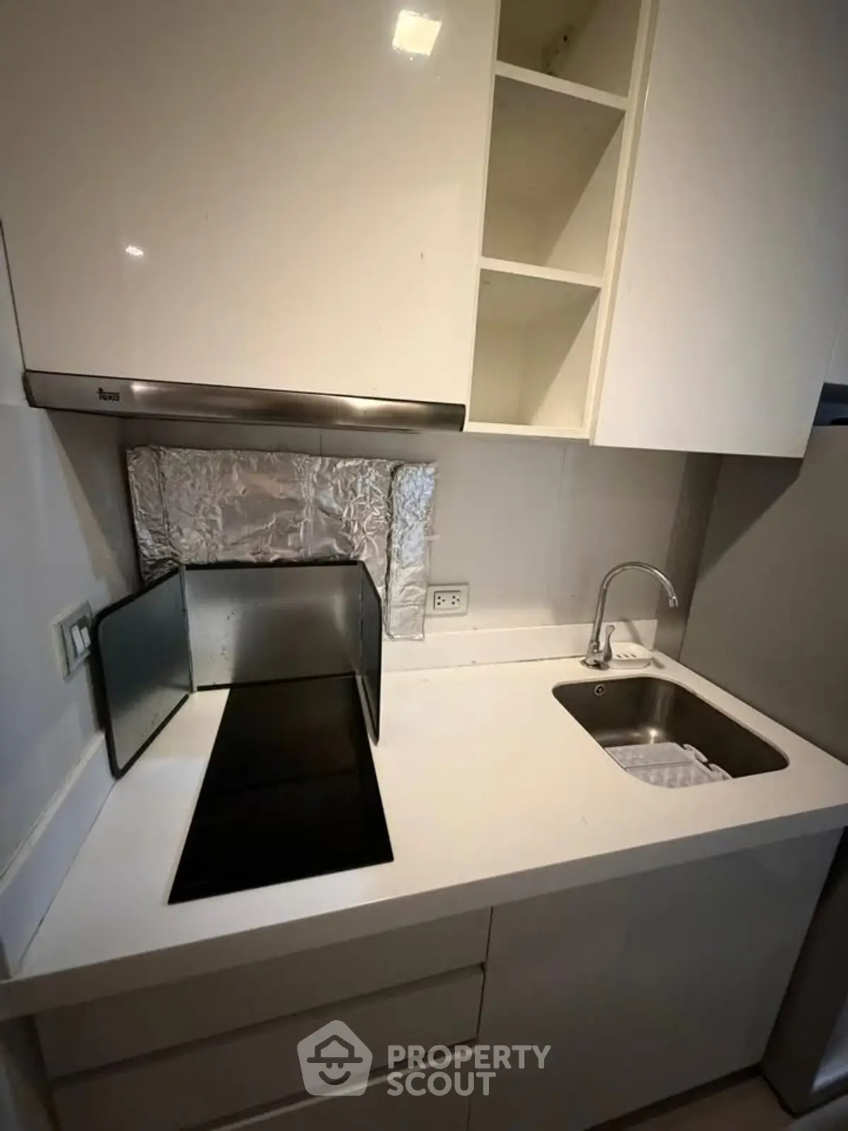 Modern compact kitchen with sleek white cabinets and electric stove