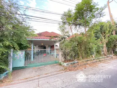 Charming single-story home with a spacious front yard, nestled among mature trees, featuring a cozy covered porch and a secure gated entrance, offering a serene suburban living experience.