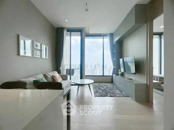 Modern living room with large windows and city view, featuring sleek furniture and stylish decor.