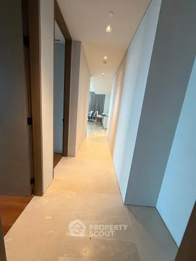 Elegant hallway leading to a modern living area with stylish decor and natural lighting.
