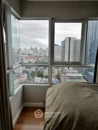 Stunning city view from a modern high-rise bedroom with large windows and elegant decor.