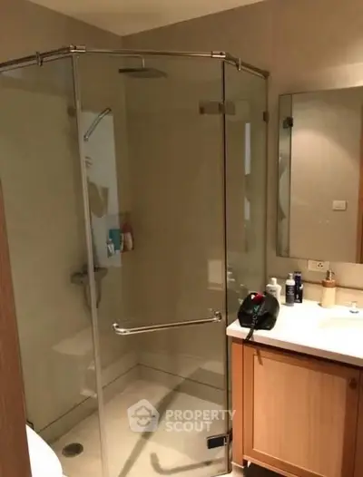 Modern bathroom with glass shower enclosure and wooden vanity unit.