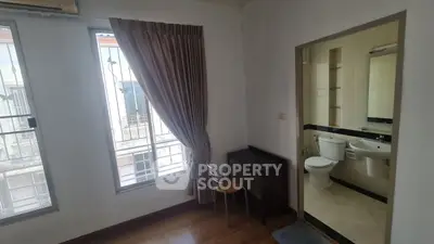 Cozy bedroom with attached bathroom, featuring large windows and elegant curtains.