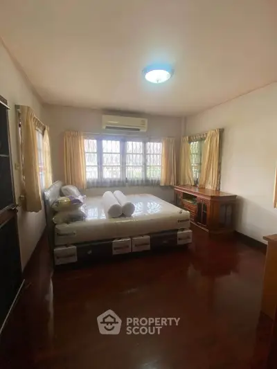 Spacious bedroom with large windows and wooden flooring