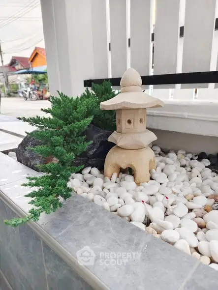 Charming garden feature with stone lantern and white pebbles, perfect for serene outdoor spaces.