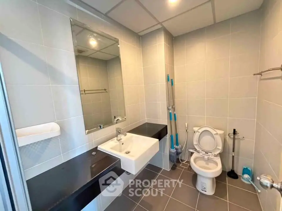 Modern bathroom with sleek fixtures and neutral tiles, featuring a spacious layout and contemporary design.