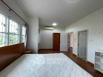 Spacious bedroom with large windows and wooden flooring in modern home