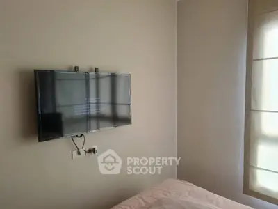 Minimalist bedroom with wall-mounted TV and natural light