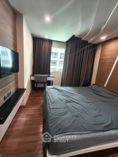 Modern bedroom with wooden flooring, stylish ceiling, and large window offering natural light.