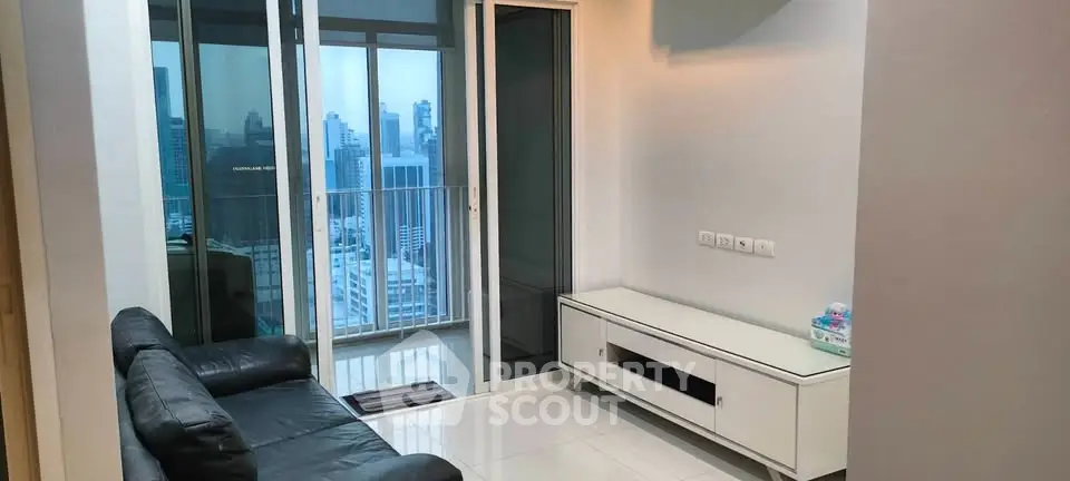Modern living room with city view and balcony access in high-rise apartment.
