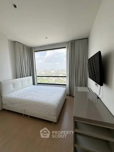 Modern bedroom with large window offering stunning city views and sleek furnishings.