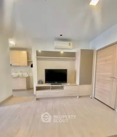 Modern living room with sleek TV unit and open kitchen layout in a stylish apartment.