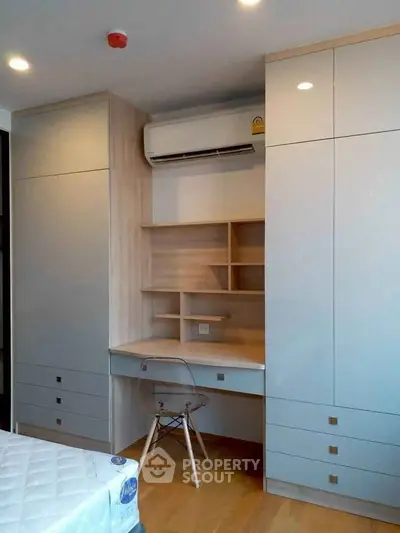 Modern bedroom with built-in wardrobe and study desk, featuring sleek design and ample storage.