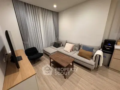 Modern living room with cozy gray sofa, wooden coffee table, and sleek TV setup.