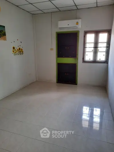 Spacious empty room with tiled floor and air conditioning, ready for customization.