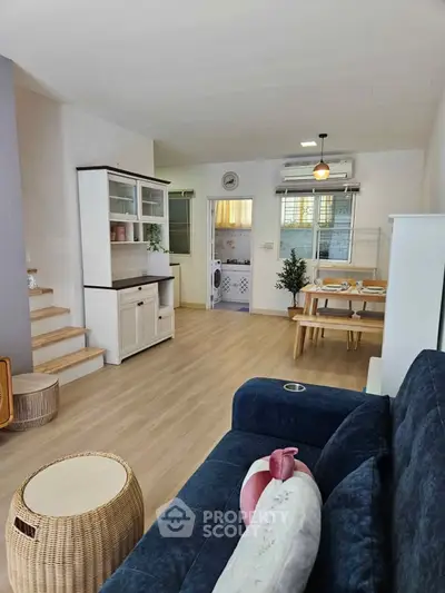 Charming open-plan living room with cozy seating and dining area, featuring modern decor and natural light.