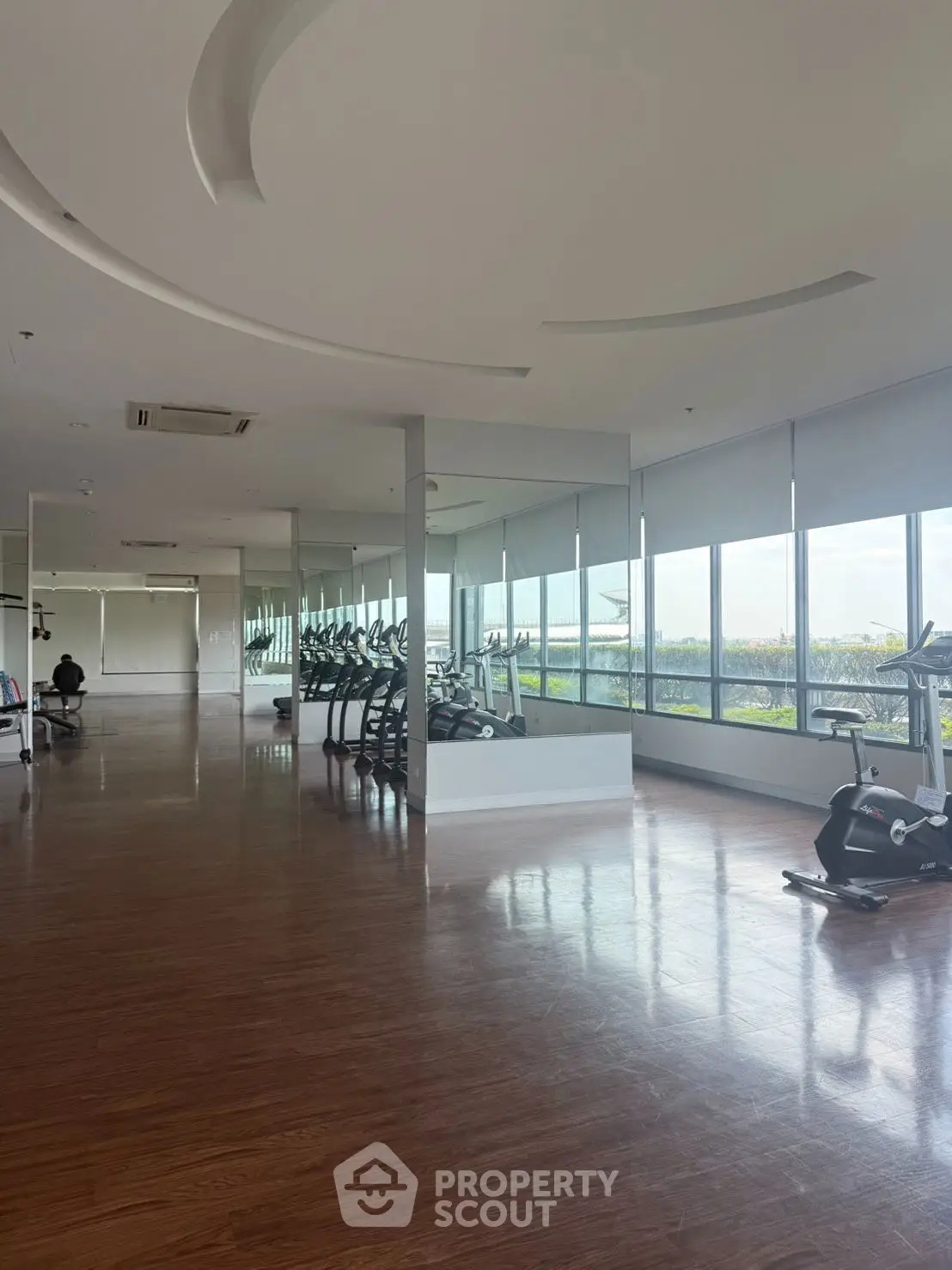 Spacious gym with modern equipment and panoramic windows in luxury real estate property.