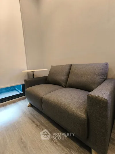 Modern living room with stylish gray sofa and sleek wooden flooring, perfect for urban living.