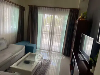 Cozy living room with natural light, modern furniture, and elegant curtains.