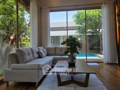 Luxurious living room with pool view, featuring elegant furniture and large windows for natural light.