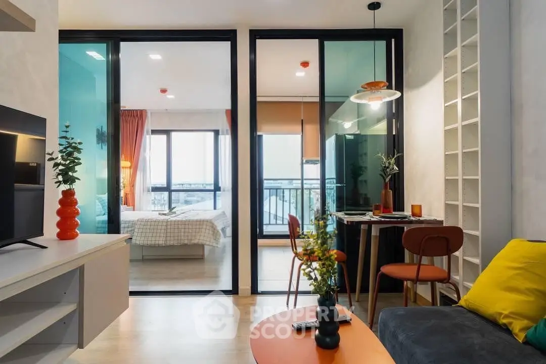 Modern living room with glass partition, cozy decor, and view into stylish bedroom