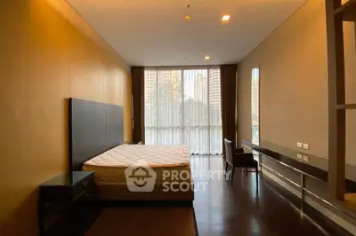 Spacious bedroom with large window and modern furnishings in a luxury apartment.