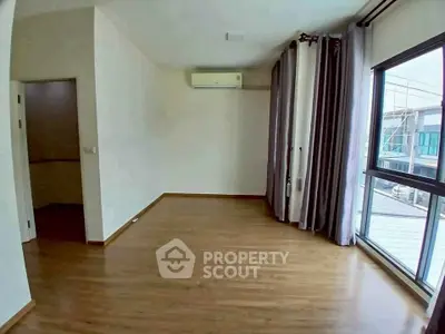 Spacious empty room with large windows and wooden flooring, perfect for customization.