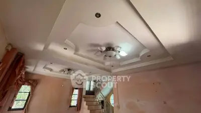 Spacious living room with elegant ceiling design and staircase, perfect for modern living.