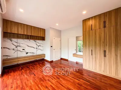 Spacious modern bedroom with wooden flooring and built-in storage