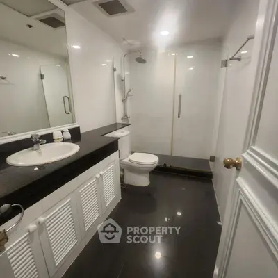 Modern bathroom with sleek black tiles and glass shower enclosure