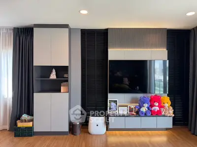 Modern living room with sleek cabinetry and large TV, featuring plush toys and stylish decor.