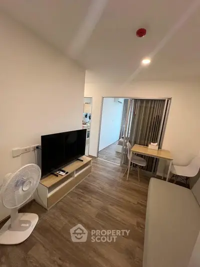 Modern living room with sleek TV setup and cozy dining area, featuring wooden flooring and minimalist decor.