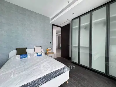 Modern bedroom with sleek design and ample natural light, featuring a stylish bed and spacious wardrobe.
