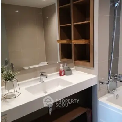 Modern bathroom with sleek sink and bathtub, featuring elegant shelving and stylish decor.