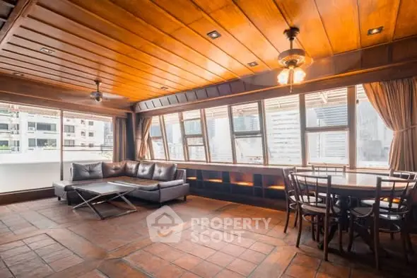 Spacious living room with wooden ceiling and large windows offering city views.