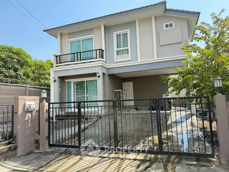 Charming two-story house with gated driveway and lush greenery, perfect for family living.