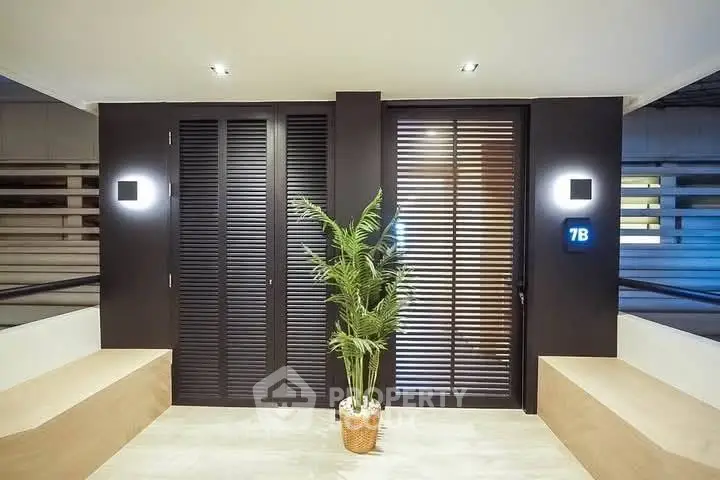 Modern apartment entrance with sleek design and potted plant, showcasing contemporary style.